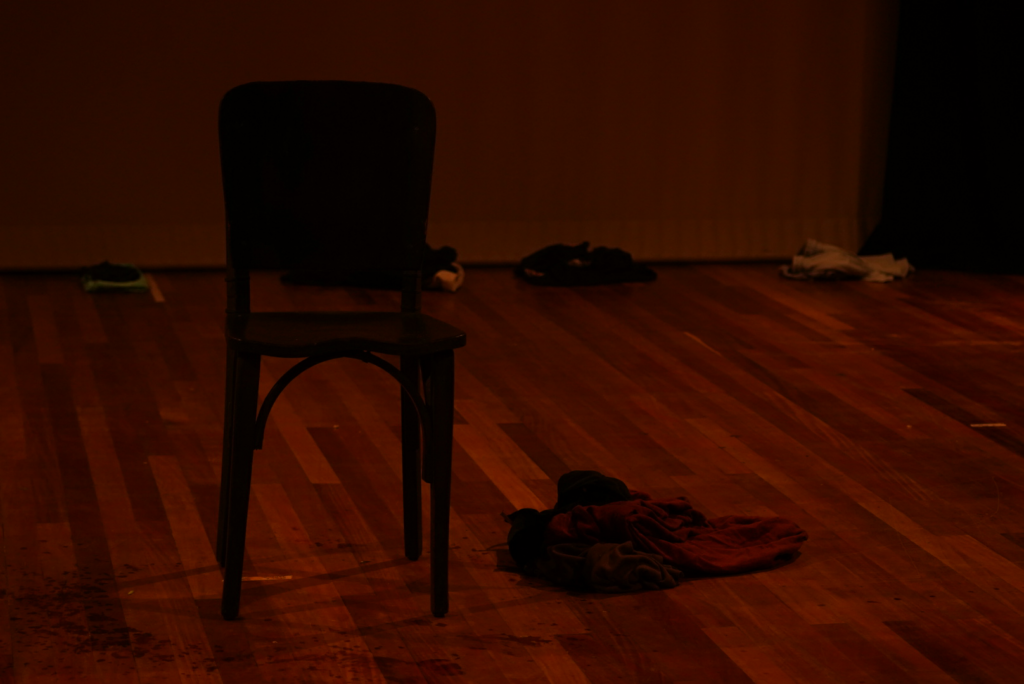 Imagem de palco com objetos espalhados: cadeira, sapatos, roupas