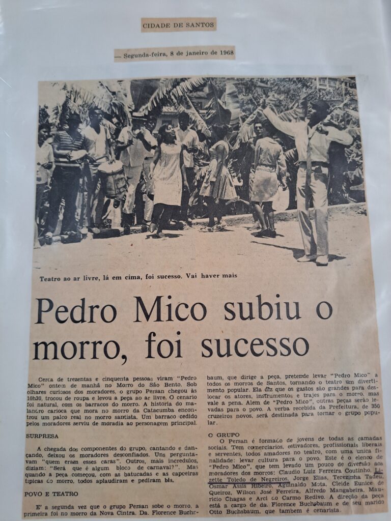 Recorte de jornal datado de segunda-feira, 8 de janeiro de 1968, intitulado "Pedro Mico subiu o morro, foi sucesso", publicado na seção "Cidade de Santos". O artigo relata uma apresentação teatral ao ar livre da peça Pedro Mico, realizada no Morro de São Bento, em Santos.A imagem central mostra um grupo de pessoas, incluindo atores e moradores, em uma encenação ao ar livre. A cena é composta por homens e mulheres, alguns carregando instrumentos musicais, enquanto outros dançam e gesticulam, interagindo com o público. No fundo, há árvores e barracos, compondo o cenário natural. O texto destaca que cerca de 350 pessoas assistiram à peça, realizada pelo grupo Persan, composto por jovens de diversas classes sociais. A apresentação foi elogiada pela integração com a comunidade local, e o enredo da peça trata de um malandro carioca que vive no morro. O artigo enfatiza a interação do teatro com o público e a recepção calorosa da plateia. Também menciona o diretor da peça, Alen, e a dramaturgia de Antonio Callado.